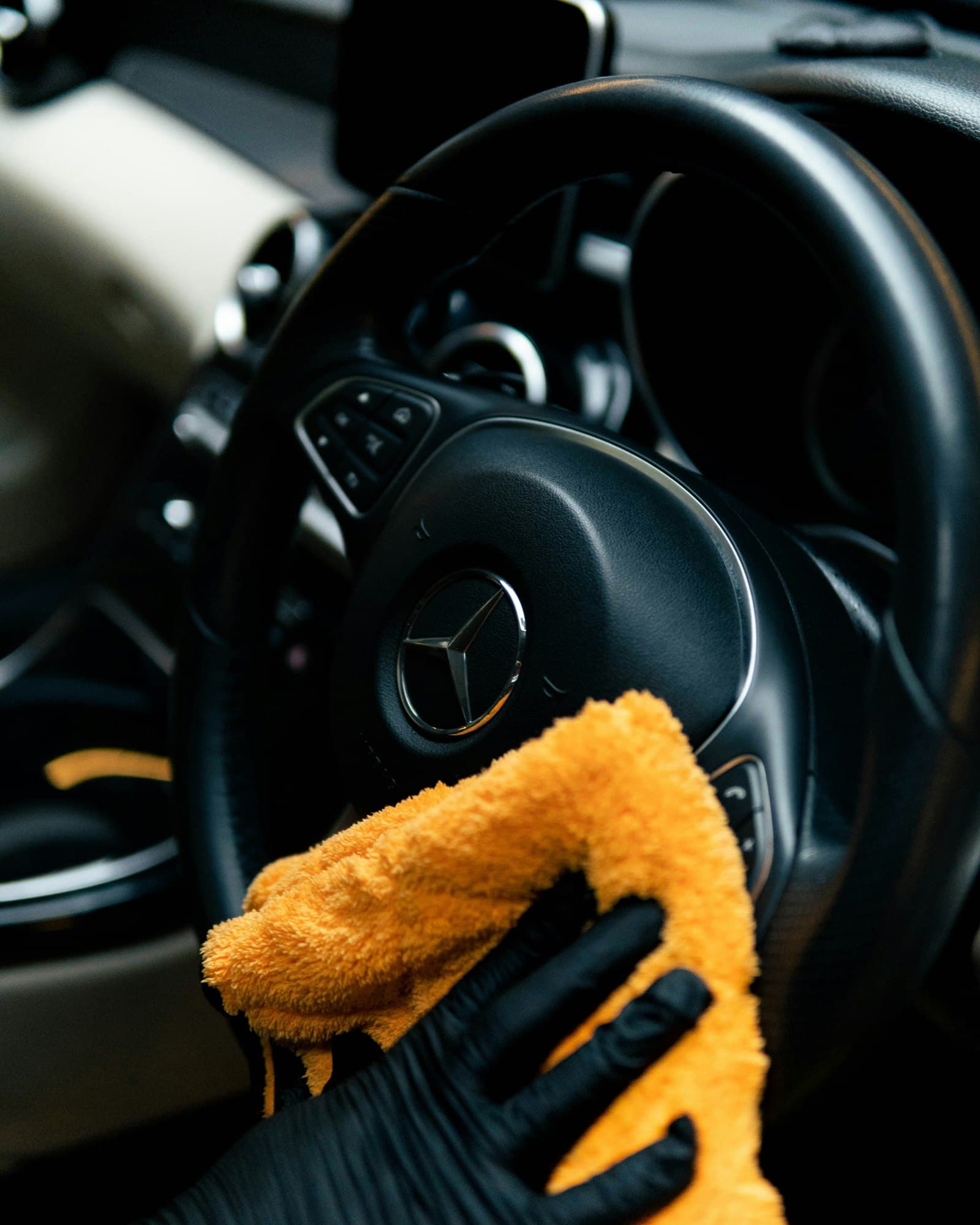 Steering wheel being wiped down with an orange microfiber towel